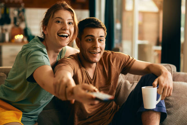 istock Young couple having fun while changing channels on TV at home. 1307641383