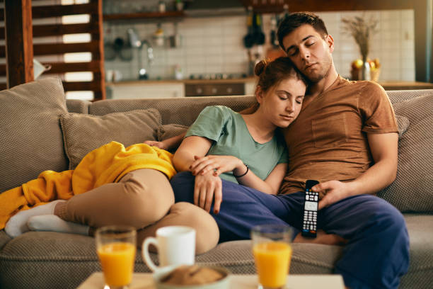 istock Young couple napping on the sofa while watching TV at home. 1307641458
