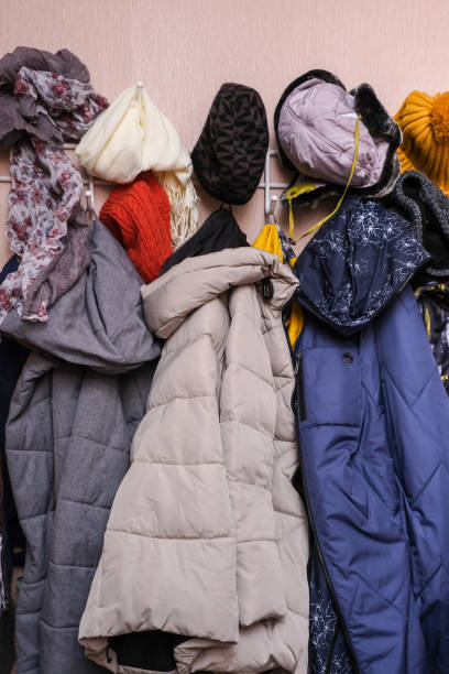 istock Many winter coats and caps, hats hanging in a mess on hooks in a corridor, decluttering warm clothes 1307641615