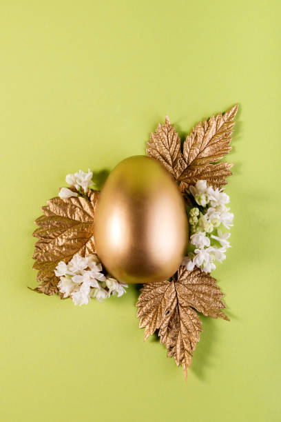 istock Trendy Easter background with Gold Easter egg and golden leaves on a light green color background with empty space for text. Easter concept. 1307642702