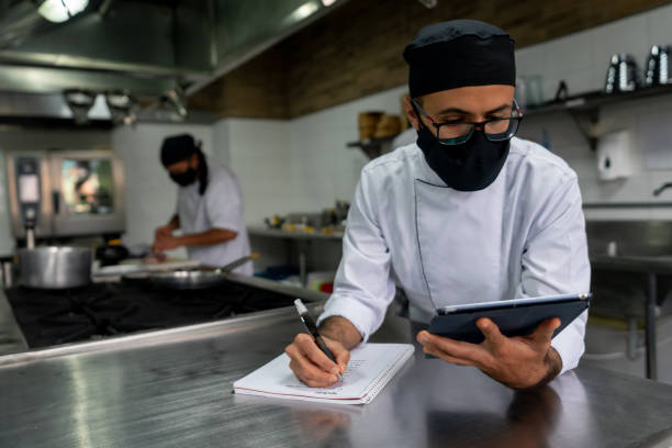 istock Chef researching a recipe while wearing a facemask in a commercial kitchen during the pandemic 1307643504
