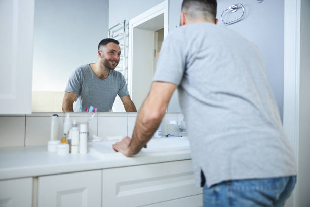istock Cheerful young man looking in the mirror in bathroom 1307643795