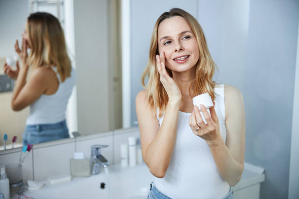 istock Beautiful woman using face cream in bathroom 1307643833