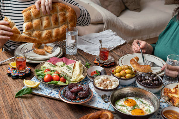 Delicious rich Traditional Turkish breakfast include tomatoes, cucumbers, cheese, butter, eggs, honey, bread, bagels, olives and tea cups. Ramadan Suhoor aka Sahur.