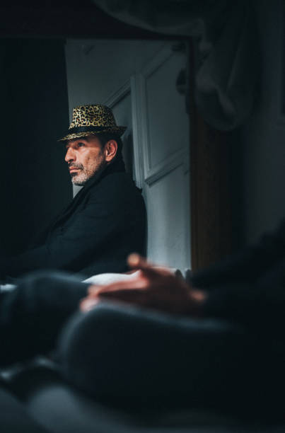 The man with the hat looks at his reflection in the mirror