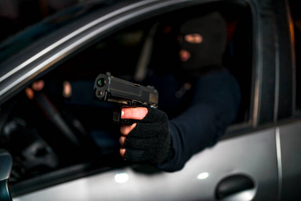 Gangster in the car Gangster with balaclava on head and a gun in his hand in the car man holding gun at night in the city stock pictures, royalty-free photos & images