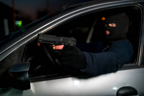 istock Masked man with handgun driving a car 1307645860