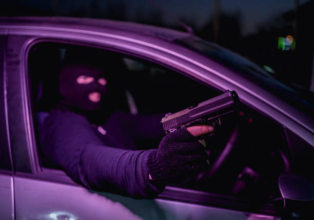 istock Masked man with handgun driving a car 1307645885