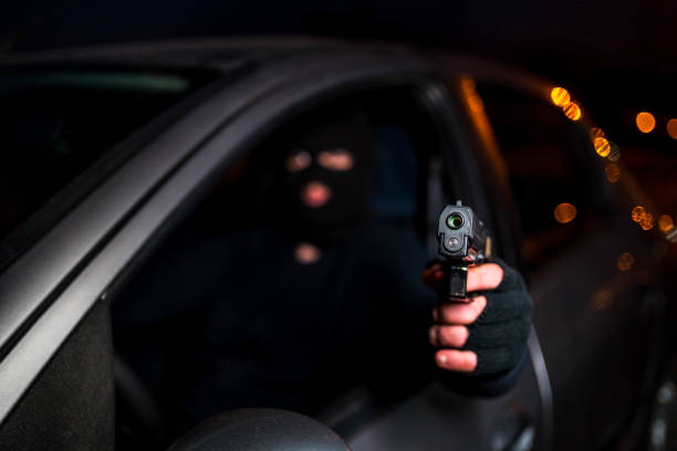 istock Masked man with handgun driving a car 1307646635