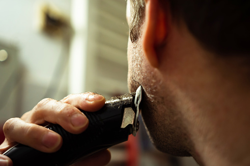 Man using electric razor for shaving his beard