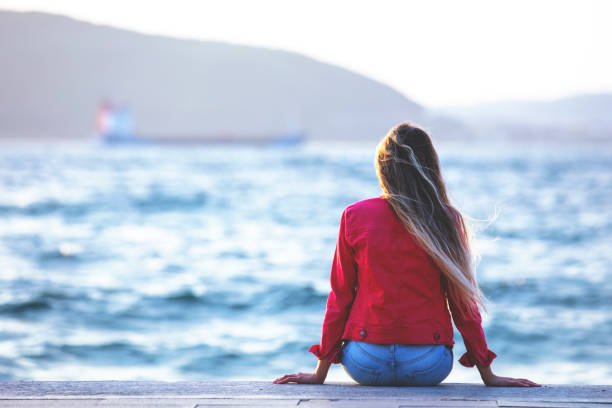 young woman watching the sea at sunset