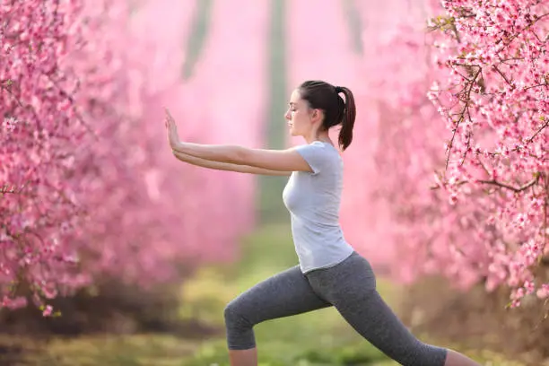 Photo of Woman doing tai chi exercise in a pink flowered field