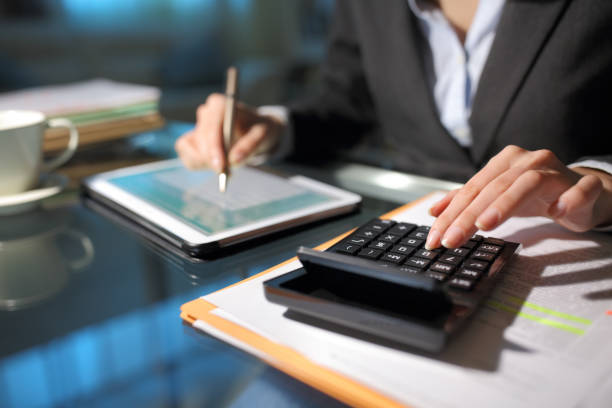 Businesswoman hands using tablet and calculator in the night stock photo