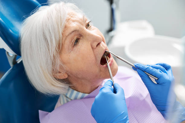 istock Orthodontist reaching inside elderly woman mouth with tools 1307652108