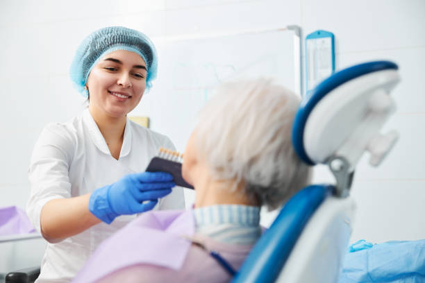 istock Young competent dental surgeon using shade guide on old person 1307652196