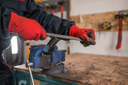 Trabajador con guantes de protección usando herramientas manuales en pequeño taller photo