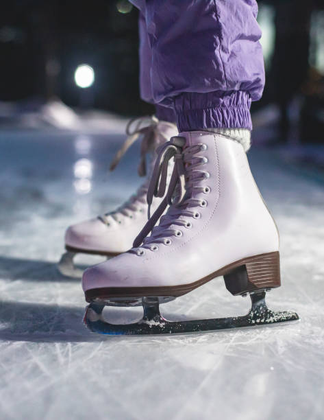 close up view of new white ice skates boots on rink in motion, girl ice skating on arena, concept of ice skating in winter, holiday christmas xmas time - ice skating ice hockey child family imagens e fotografias de stock