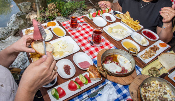 istock Family having delicious rich traditional Turkish breakfast include tomatoes, cucumbers, cheese, butter, eggs, honey, bread, olives, jam, sausage, fried potatoes and tea cups. 1307656257