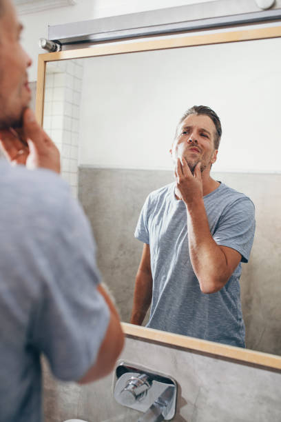 istock Handsome Young Man Checking his Beard in a Bathroom Mirror 1307656342