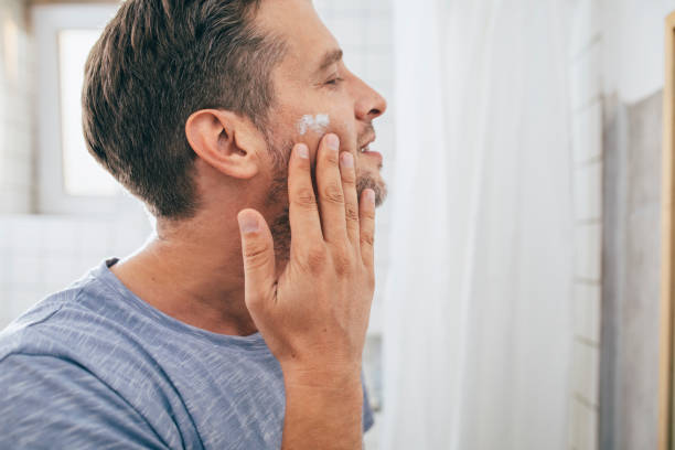 istock Handsome Young Man Applying Aftershave Moisurizer after a Morning Shave 1307656389
