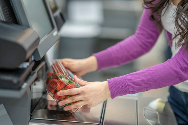 foto conceptual de una mujer escaneando fresas en el servicio de auto-pago de la tienda de comestibles - consumption scale fotografías e imágenes de stock