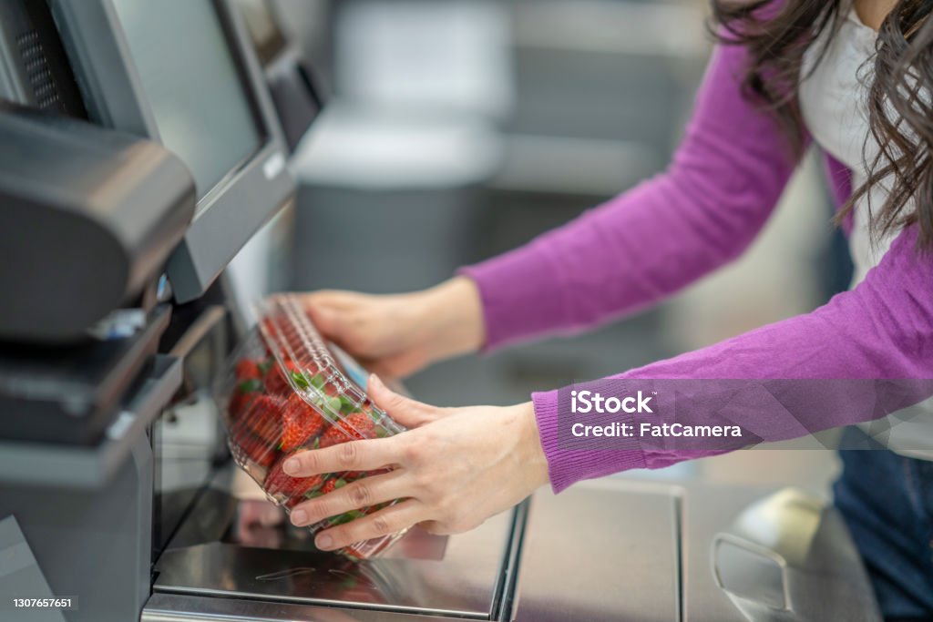Concept Photo of a Woman Scanning Strawberries at the Grocery Store Self Checkout Service A photo showing a woman's hands scanning a box of strawberries at the grocery store's self check out service. Supermarket Stock Photo