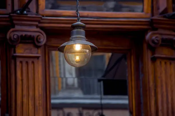 retro hanging lantern in loft style with an electric bulb glows with a warm light in the interior of a cafe with wooden frames with rustication close-up, nobody.