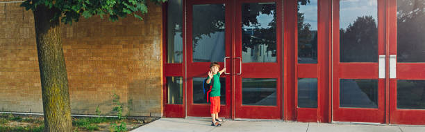 little happy caucasian boy student with backpack waving hand farewell. kid opening door on 1 september day. education back to school. child ready to learn, study. web banner header for a website. - little boys preschooler back to school backpack imagens e fotografias de stock