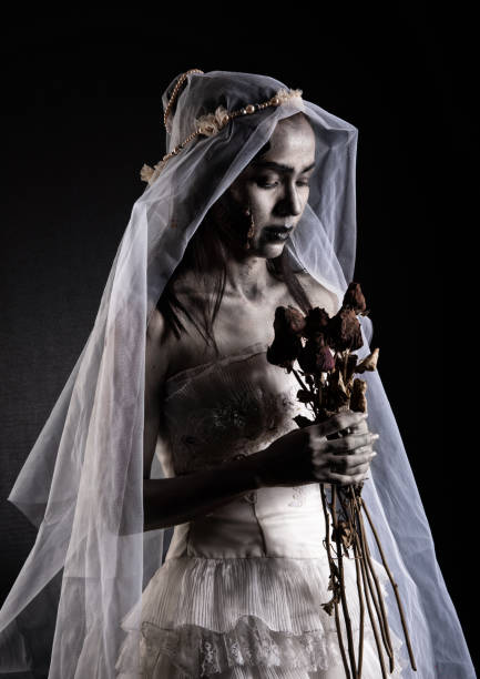 Horror Scene of a Possessed bride Woman in white dress Horror Scene of a Possessed bride Woman in white dress black long hair ghost zombie holding dried Rose Bouquet on hand in dark room isolated. halloween scary concept scary bride stock pictures, royalty-free photos & images