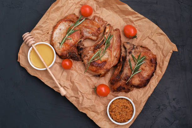 istock Roasted pork loin steaks with herbs and spices on baking paper. 1307672689
