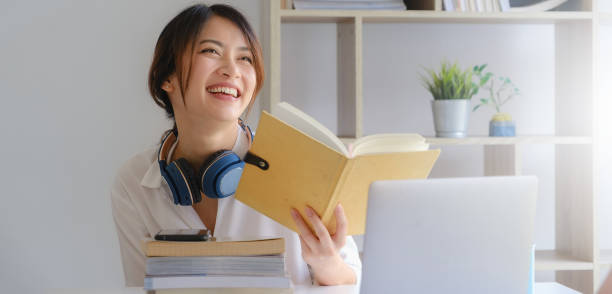 verticale de fille asiatique de sourire d’étudiant et affichant un livre à l’école à la maison avant d’apprendre la classe en ligne virtuelle d’internet. pandémique covid. - book working college student classroom photos et images de collection