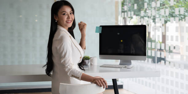 アジアのビジネスウーマンの肖像画は、彼女のオフィスで笑顔と座っています。 - senior manager ストックフォトと画像