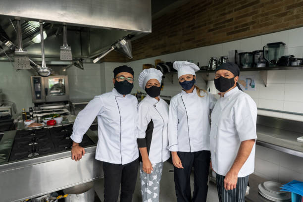 istock Chef and a group of cooks wearing facemasks while working in a kitchen 1307676688