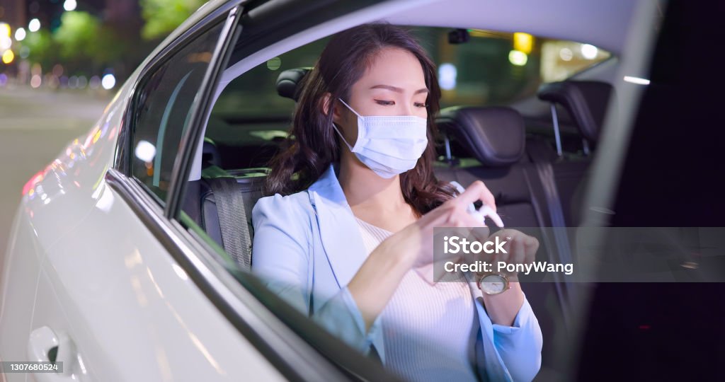 businesswoman use hand sanitizer asian successful businesswoman wearing face mask use alcohol hand sanitizer while commuting in the cab at night 20-29 Years Stock Photo