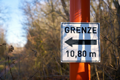 Sign with direction arrow and inscription border 10,80 meters at a forest road in Germany