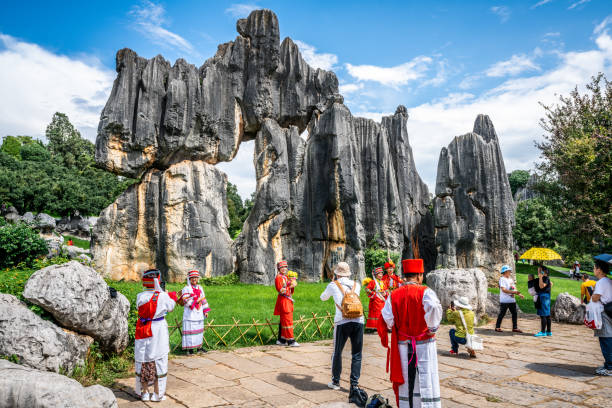 turistas chineses em vestido tradicional posando em frente à famosa tela de pedra na floresta de pedra shilin yunnan china - the stone forest - fotografias e filmes do acervo