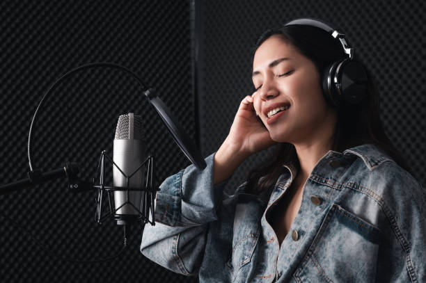 istock Asian female singer with a passion for music and microphone. While playing her guitar in a professional studio. Music concept, sound recording concept. 1307690770