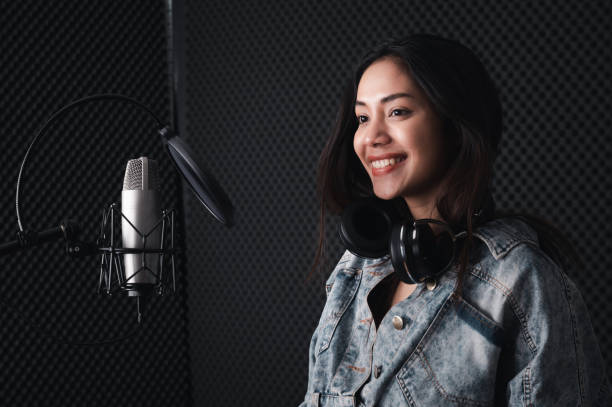 istock Asian female singer with a passion for music and microphone. While playing her guitar in a professional studio. Music concept, sound recording concept. 1307690793