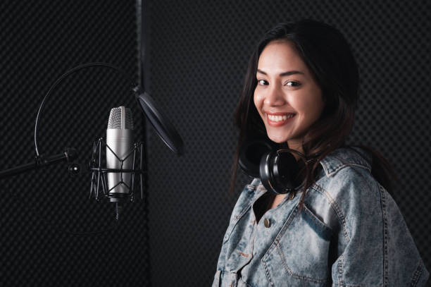 istock Asian female singer with a passion for music and microphone. While playing her guitar in a professional studio. Music concept, sound recording concept. 1307690831