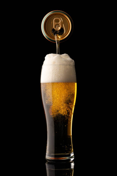 pouring beer into glass isolated on black background stock photo