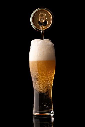 pouring beer into glass isolated on black background