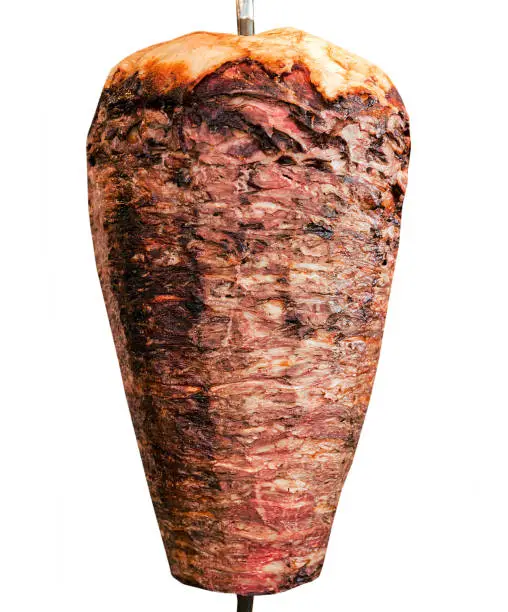 Doner kebab. Shawarma consisting of meat cut into thin slices, stacked in a cone-like shape, and roasted on a slowly-turning vertical rotisserie or spit. Isolated on white background