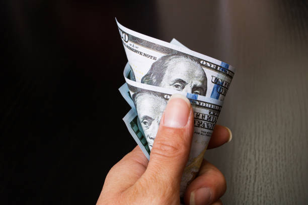 istock Hand holds rumpled dollars on wooden background 1307695537