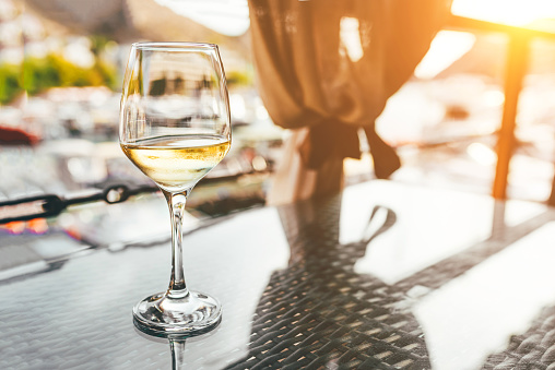 A glass of white wine on the table of a summer cafe.