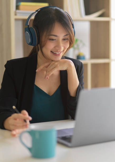 istock Happy businesswoman smiling and using headphone while working with laptop 1307705580