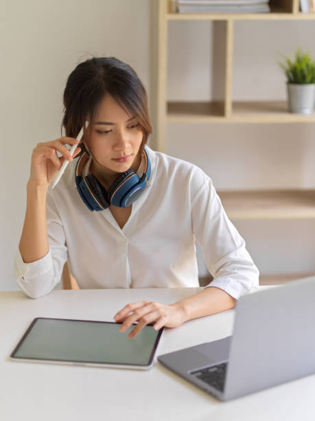istock Portrait of female worker thinking about her work while using digital tablet and laptop 1307706718