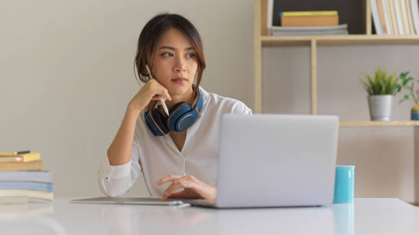 istock Female student thinking about her homework while using digital tablet and laptop in living room 1307706801