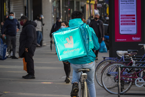 London, UK - 5 February, 2021 - Deliveroo worker (zero-hour contract employment) riding on Wood Green high street