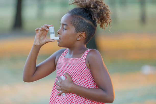 istock Young African-American Girl with Asthma is Using Inhaler in a Park. 1307711073