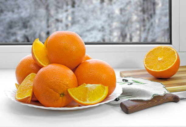istock Oranges on a plate on the sill of the window. 1307711272